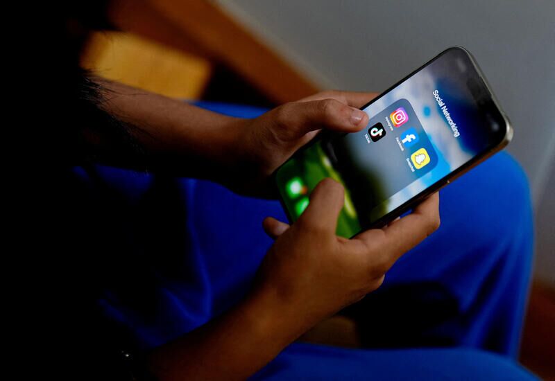 A high school student poses with her mobile showing her social media applications in Melbourne, Australia.